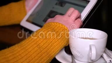 年轻女孩<strong>坐</strong>在餐桌旁的咖啡馆里，用平板电脑。 这个女孩正在修改社交网络。 <strong>双手</strong>特写..